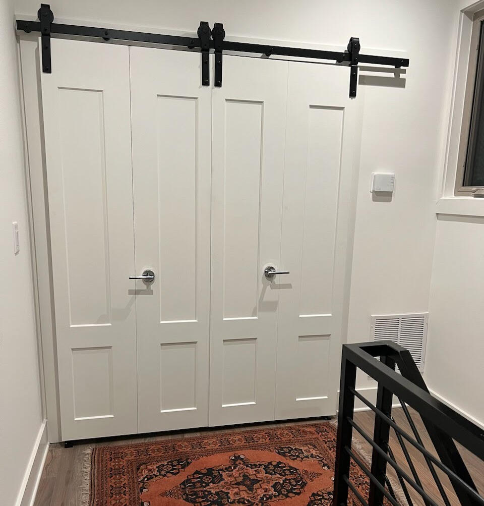 Handy Dandy Atlanta — custom double white barn doors with black sliding hardware installed above a Persian-rug hallway