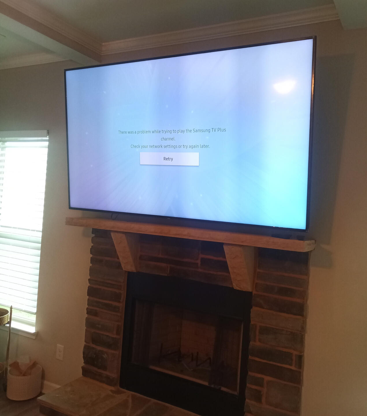 Handy Dandy Atlanta — large flat-panel TV mounted above a brick fireplace with a rustic wood mantel, wires concealed through the mantel